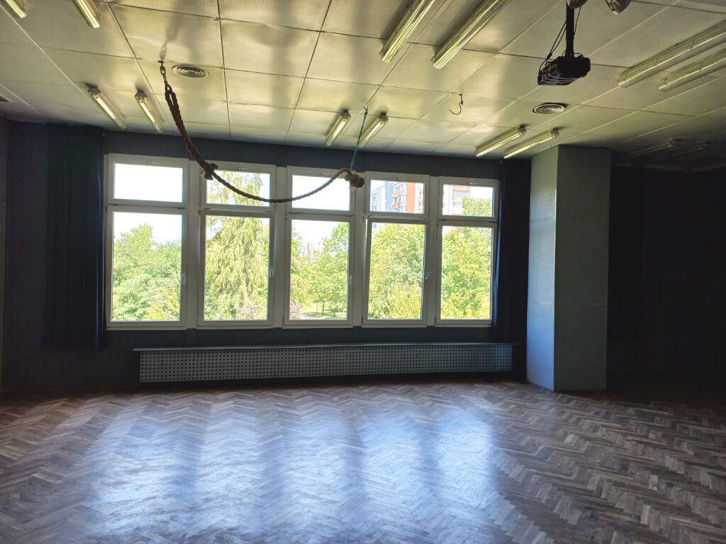 Sala widowiskowa Domu Kultury – parkiet i duże okna z widokiem na zieleń